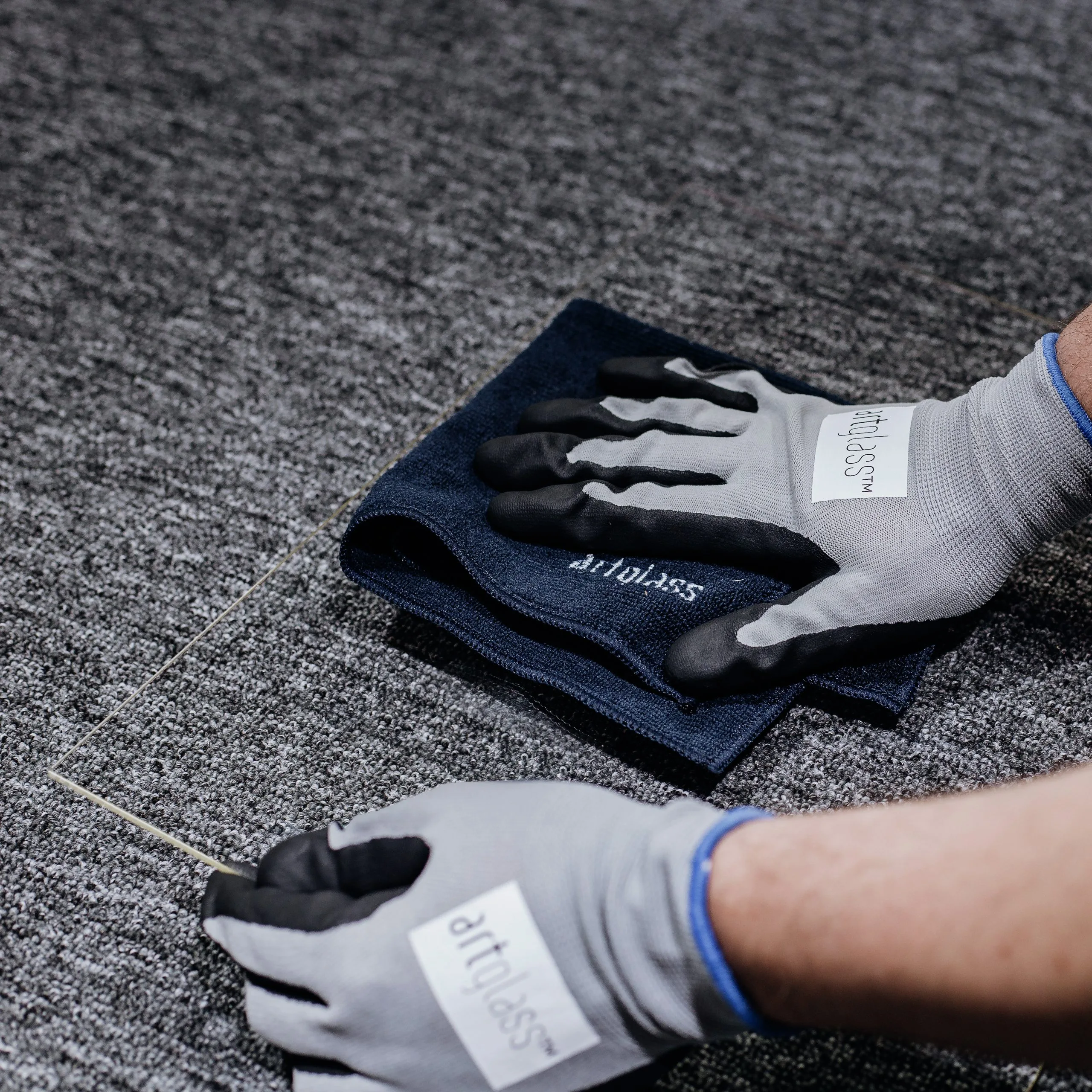 Gloved hands cleaning an Artglass sheet with a microfiber cloth