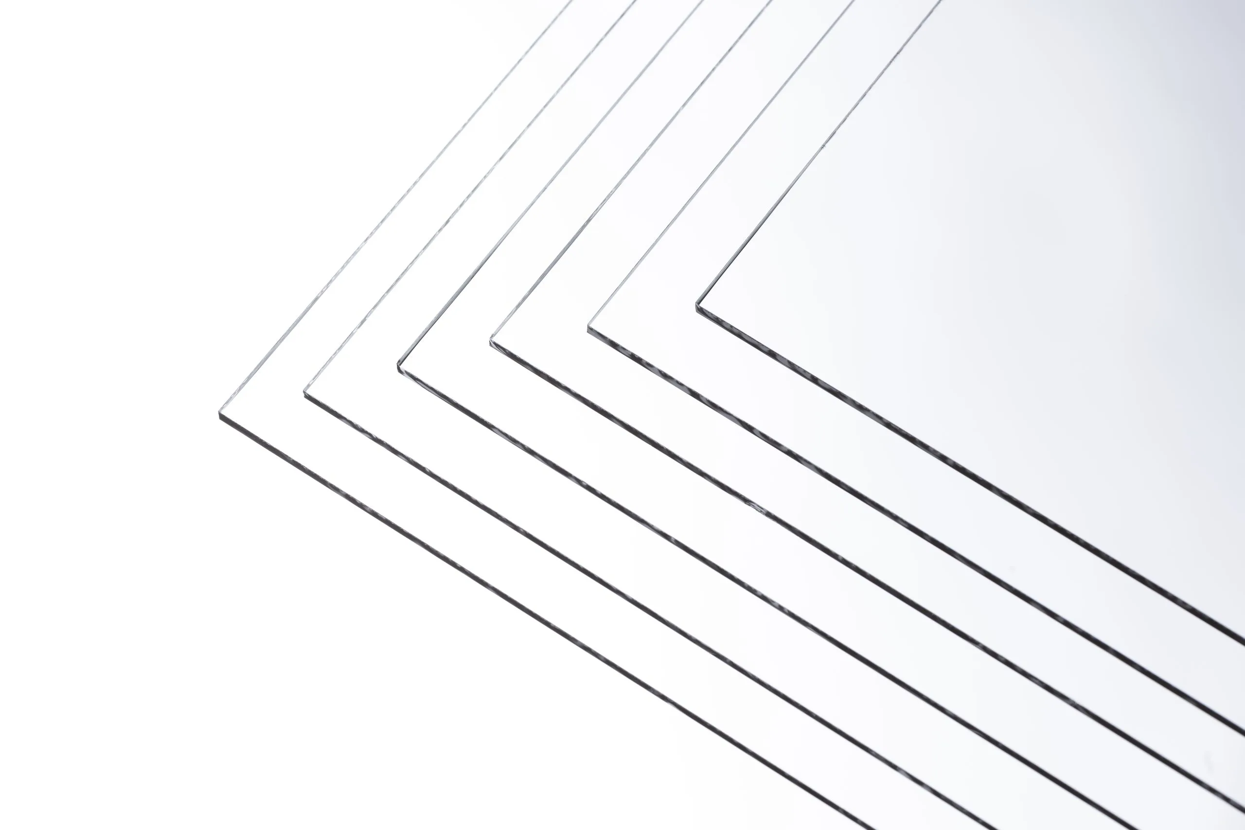 Nearly invisible Artglass sheets fanned out on a white surface, only their edges visible